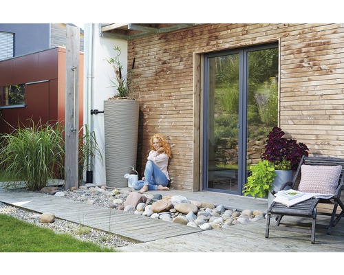 Garten mit Regenwassertank, Außendusche und Holzterrasse.