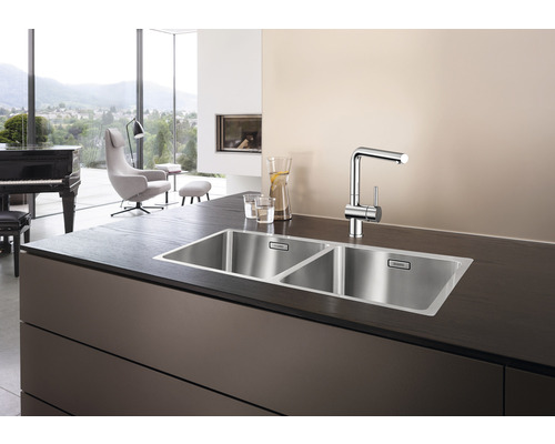 Edelstahlspüle mit zwei Becken und Armatur auf einer Arbeitsplatte.