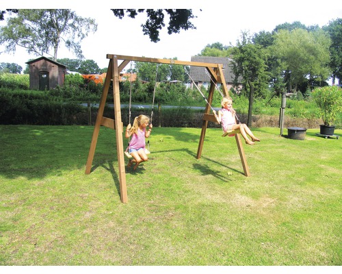 Freistehende Holzschaukel mit zwei schaukelnden Kindern im Garten.