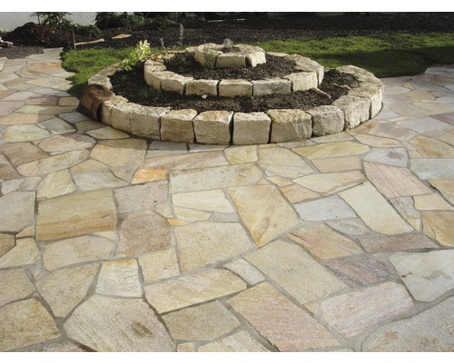 Außenbereich mit Natursteinpflaster und spiralförmigem Hochbeet