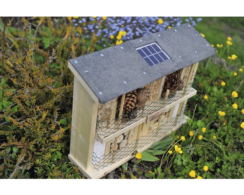 Insektenhotel aus Holz mit Solarpanel auf dem Dach im Garten