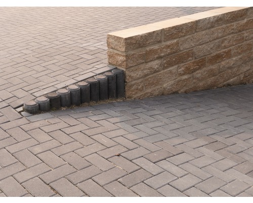 Außenbereich mit Pflastersteinen, Palisaden und einer Steinmauer