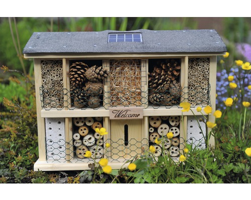 Insektenhotel mit verschiedenen Füllmaterialien wie Kiefernzapfen, Holz und Stroh