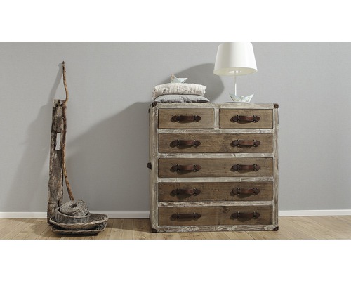 Kommode mit mehreren Schubladen und Ledergriffen, zusammen mit einer Stehlampe und dekorativen Körben