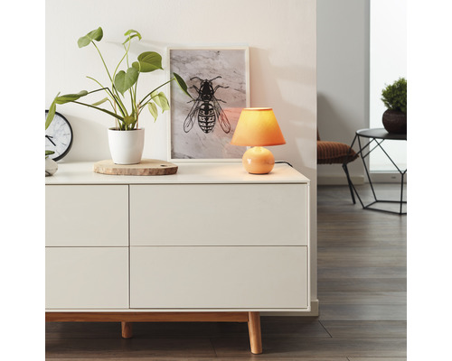 Kommode mit Dekoration wie Tischleuchte, Topfpflanze und Bild