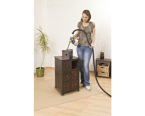 Frau lackiert mit Farbsprühsystem einen Nachttisch