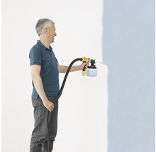 Ein Mann verwendet ein Farbsprühgerät, um eine Wand zu streichen.