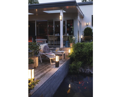 Beleuchtete Terrasse mit Gartenmöbeln und Teich mit Fischen