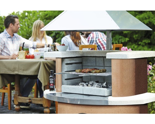 Gemauerter Gartengrill mit Grillgut, Grillkohle und Jack Daniel''s Barbecue Sauce im Garten mit Menschen