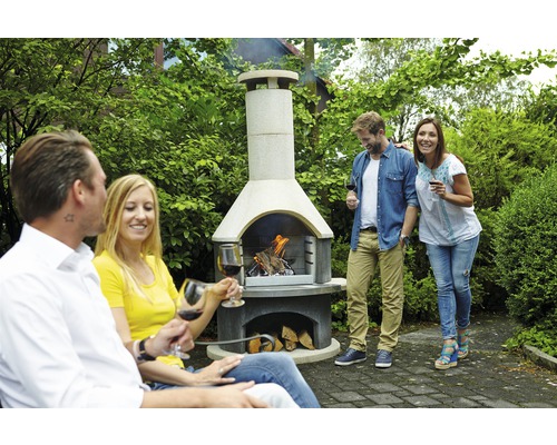 Grillkamin mit brennendem Holz und Menschen im Garten.
