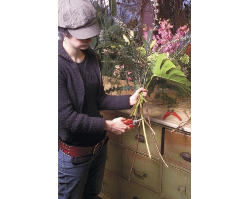 Frau schneidet Blumen mit einer Gartenschere für ein Blumengesteck