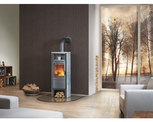 Wohnzimmer mit Kaminofen, Brennholz und Fenster mit Winterlandschaft