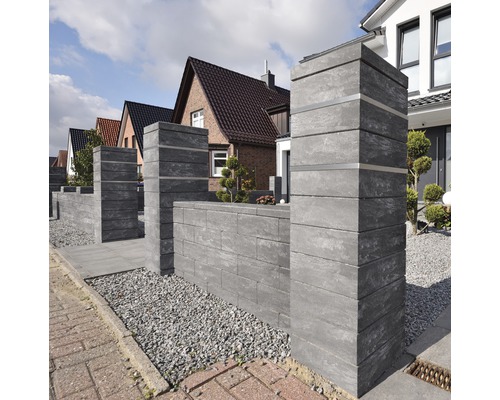 Gestapelte Gartenmauersteine aus Beton begrenzen ein Grundstück.