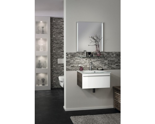 Badezimmer mit Waschtisch, Spiegel, Steinwand und Toilette.