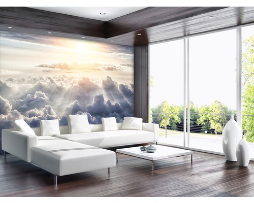 Heller Wohnraum mit Wolkenhimmel-Fototapete, Sofa und großen Fenstern