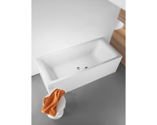 Rechteckige Badewanne aus Sanitäracryl mit Überlauf und Handtuch auf einem Hocker