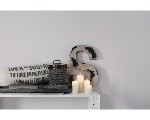 Dekorative Szene mit Kissen, Dose, Kerzen und einem Buchstaben auf einem Regal