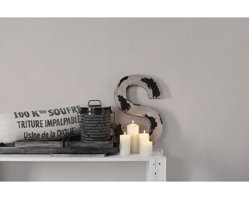 Dekorative Szene mit Kissen, Dose, Kerzen und Dekobuchstabe auf einem Regal