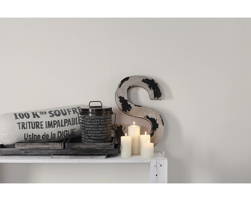 Dekoration mit Kissen, Behälter, Kerzen und Buchstabe auf einem Regal