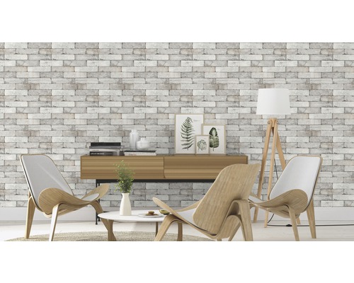 Wohnzimmer mit Wandtapete in Steinoptik, zwei Sesseln und einer Kommode.