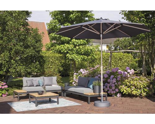 Gartenlounge unter einem Sonnenschirm auf einer Terrasse mit Ziegelboden