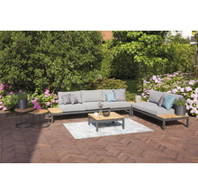 Gartensitzgruppe mit Sofa, Liege, Couchtisch und Beistelltischen auf einer Terrasse mit Blumen im Hintergrund.