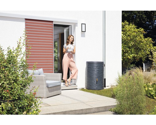 Regentonne im Garten neben einer Frau und einem Haus