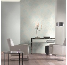 Heller Wohnraum mit floral gemusterter Tapete, Sesseln und Stehlampe.