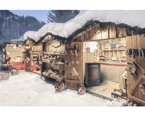 Wintermarkt mit Holzbuden, dekoriert mit Weihnachtsschmuck und beleuchtet, und einem Heizgerät.