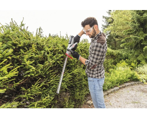 Mann schneidet Hecke mit einer Heckenschere