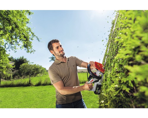 Ein Mann schneidet eine Hecke mit einer Akku-Heckenschere der Marke AL-KO.