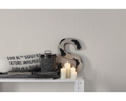 Dekoratives Arrangement mit Kissen, Dose, Kerzen und einem S auf einem Regal