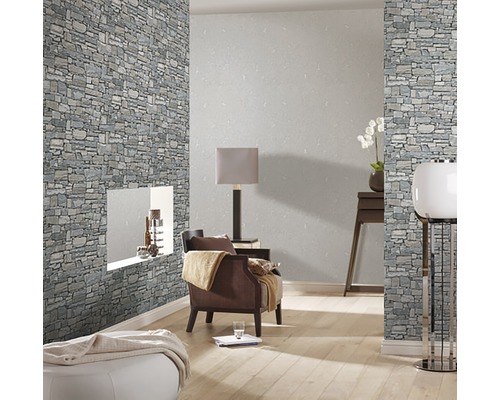 Wohnzimmer mit Steinwandtapete, Sessel und Stehleuchte