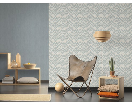 Wohnzimmer mit gemusterter Tapete, Sessel und Holzregal