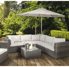 Gartenszene mit Lounge-Set aus Rattan, Tisch, Sonnenschirm, Sektkübel, Gläsern und Kerzen auf einer Holzterrasse
