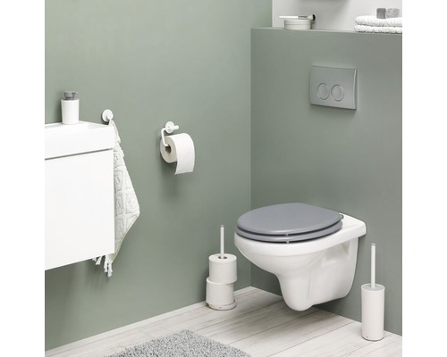 Modernes Badezimmer mit Wandtoilette, Toilettenpapierhalter, Toilettenbürste und Waschbeckenunterschrank.