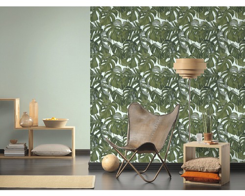 Wohnraum mit Monstera-Blatt-Tapete, Sessel und Holzmöbeln für ein helles und organisiertes Ambiente.