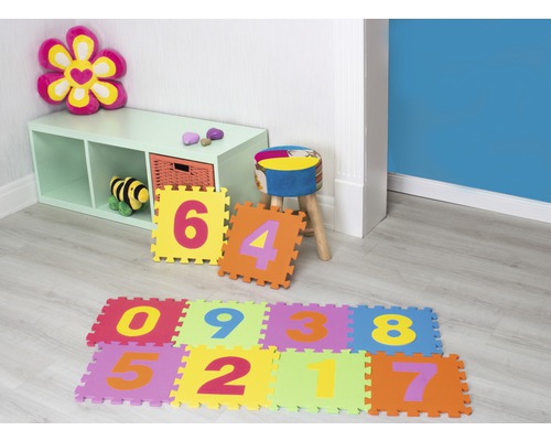 Spielzimmer mit Regalen, Hocker und bunten Schaumstoffmatten mit Zahlenmotiven.