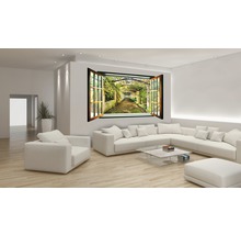 Wohnzimmer mit Sofa, Sessel, Glastisch und Wandtattoo in Fensteroptik mit Gartenmotiv.