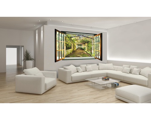 Wohnzimmer mit Sofa, Sessel, Glastisch und Wandtattoo in Fensteroptik mit Gartenmotiv.