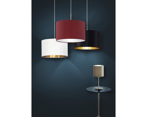 Drei Textil-Hängeleuchten mit unterschiedlichen Lampenschirmfarben und eine Tischleuchte auf einem Beistelltisch.