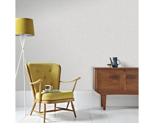 Einrichtungsbeispiel mit gemusterter Tapete, Sessel, Stehlampe und Kommode