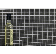 Essigessenz in Glasflasche vor dunklem Mosaikhintergrund