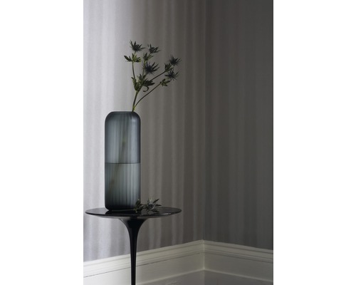 Dekorative Glasvase mit Blume auf einem Beistelltisch vor gestreifter Tapete.