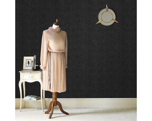 Ein Zimmer mit einer Schaufensterpuppe, einem kleinen Tisch und einer Wand mit Tierhautmuster