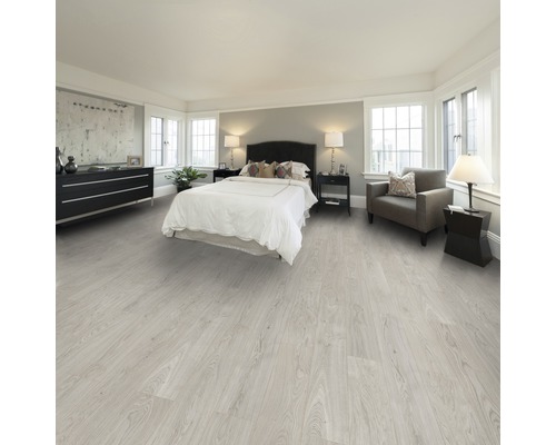 Helles Schlafzimmer mit Bett, Kommode, Sessel und hellem Holzboden