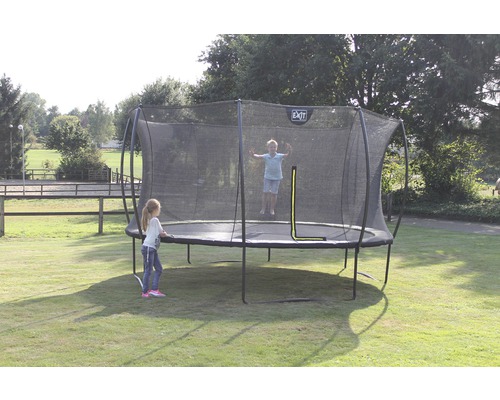 Trampolin mit Sicherheitsnetz im Garten mit spielenden Kindern