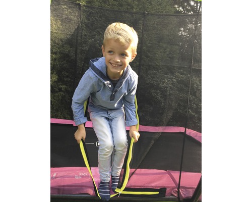 Junge klettert auf Gartentrampolin mit Sicherheitsnetz