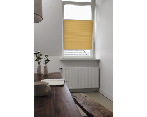 Gelbe Faltjalousie am Fenster in einem hellen Raum.