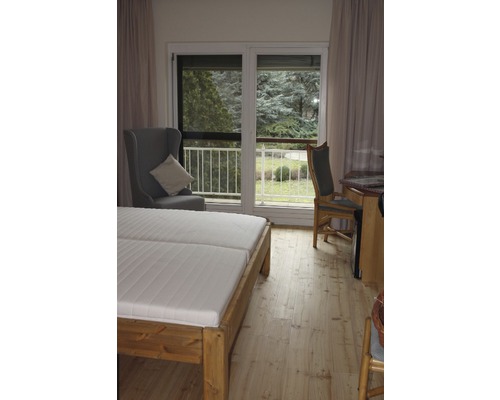 Schlafzimmer mit Doppelbett, Sessel und Zugang zum Balkon.